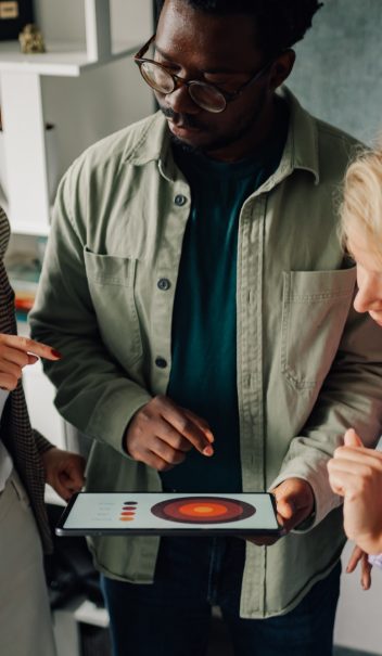 Marketing team analyzing charts on digital tablet in office meeting Marketing team analyzing charts on digital tablet in office meeting